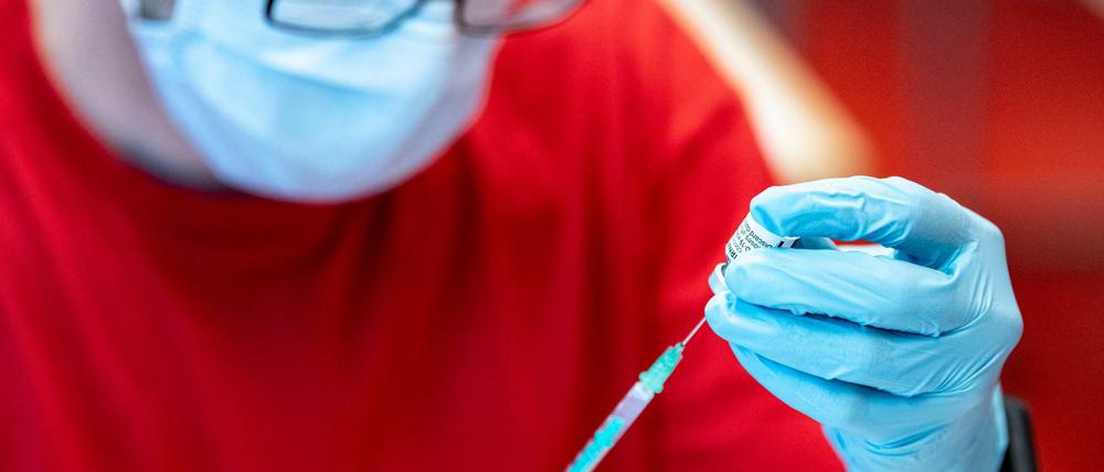 Eine Notfallsanitäter der DLRG zieht an der Universität Potsdam den Corona-Impfstoff von Biontech in eine Spritze.