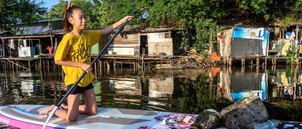Die 12-Jährige Ralyn Satidtanasarn, Spitzname Lilly, sammelt mit ihrem Paddelbrett Plastikmüll in einem Kanal in Bangkok.