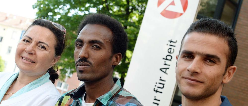 Flüchtlinge aus Afghanistan, Eritrea und Syrien vor einem Schild der Agentur für Arbeit in Hannover.