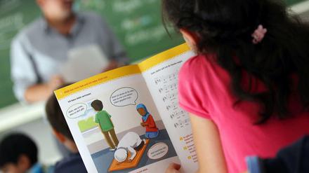 Ein Mädchen liest an einer Bonner Schule während des islamischen Religionsunterrichts in einem Schulbuch.