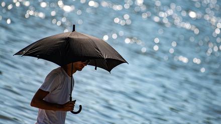 Ein Mann schützt sich in Göttingen mit einem Regenschirm vor der Sonne (Symbolbild).