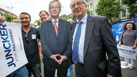 Ironie im Wahlkampf. Die Unterstützung der Kanzlerin für Juncker hält sich in Grenzen - trotzdem präsentiert der Kandidat einen Pappkameraden mit "Merkel-Raute". 