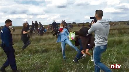 Eine Kamerafrau des ungarischen Senders N1TV stellt in Röszke einem Flüchtling, der ein kleines Kind auf dem Arm trägt, ein Bein.