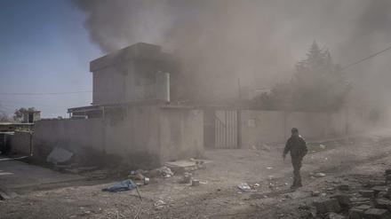 Ein Mann geht in Mossul, Irak, in der Nähe des Flughafens an einem in Brand gesetzten Haus vorbei.