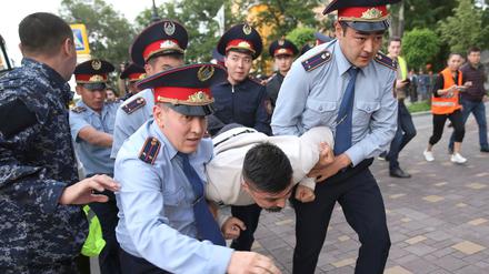 Polizisten in Almaty nehmen einen Demonstranten fest.