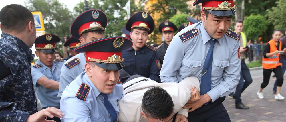 Polizisten in Almaty nehmen einen Demonstranten fest.