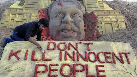 Sandskulptur mit einem Toten und dem Text "Don't kill innocent people"