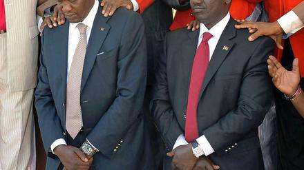 Kenyatta und Ruto knieen vor mehreren Priestern, die sie festhalten