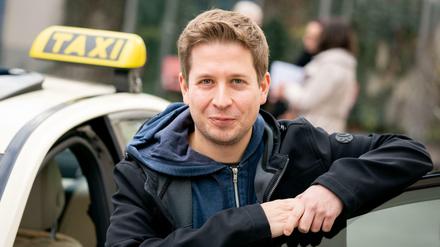 Kevin Kühnert, stellvertretender Bundesvorsitzender der SPD, steht nach der Besichtigung der Taxizentrale von Taxi Berlin an einem Taxi. 