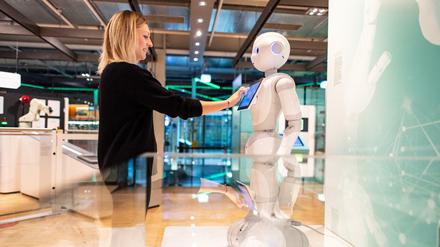Die Kuratorin Judith Spickermann steht in der Ausstellung: "Künstliche Intelligenz und Robotik" im Heinz Nixdorf MuseumsForum vor einem Serviceroboter Namens Pepper. 
