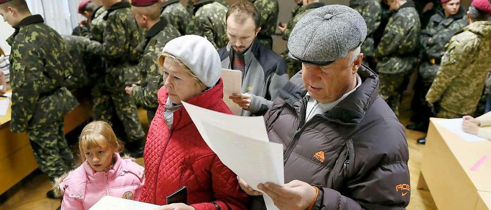 Eine Familie und ziemlich viele Soldaten bei der Abstimmung in einem Wahllokal in Kiew.