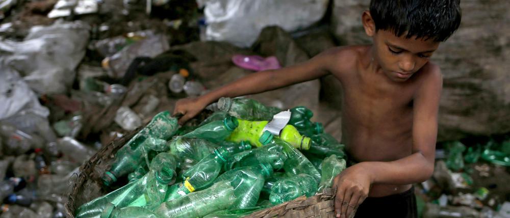 Siyam (10) sortiert in Dhaka (Bangladesch) Plastikflaschen in einer Recylingfabrik. 