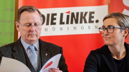 Bodo Ramelow durchblättert den Koalitionsvertrag von Die Linke, SPD und Bündnis 90/Die Grünen, neben ihm sitzt die Linken-Politikerin Susanne Hennig-Wellsow.