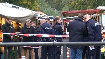 Polizeibeamte stehen am 17.10.2015 in Köln am Tatort am Braunsfelder Wochenmarkt. Die Kölner Oberbürgermeisterkandidatin Henriette Reker ist einen Tag vor der Wahl bei einer Messerattacke in Köln verletzt worden. 