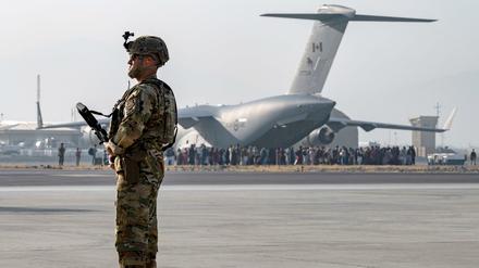 Ein US-Soldat der US-Luftwaffe bewacht die Evakuierte von Nichtkombattanten mit einem Flugzeug vom Typ C-17 Globemaster III.