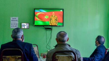 Drei Männer verfolgen in Barda, Aserbaidschan, im Fernsehen eine Ansprache von Ilham Aliyev, Präsident von Aserbaidschan. 