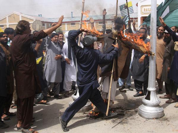 Ein pakistanischer Mann schlägt auf ein brennendes Bild des indischen Premierministers Modi ein.