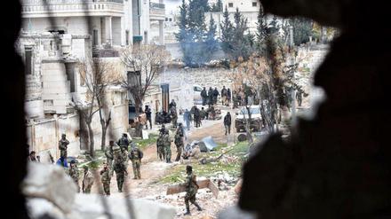 Bewaffnete Soldaten der syrischen Regierung stehen in einer Straße Aleppos. 