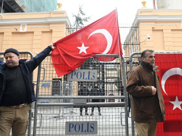 Männer halten die türkische Nationalflagge vor dem russischen Konsulat.