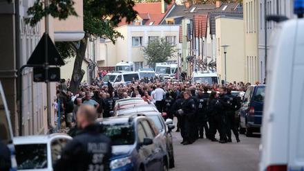 Menschen stehen umgeben von Polizisten in der Innenstadt von Köthen.
