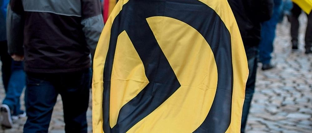 Ein Mann mit einer Fahne mit Logo der Identitären Bewegung bei einer Kundgebung (Archivbild)