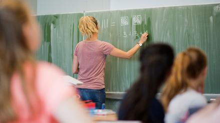 Eine Lehrerin schreibt an eine Schultafel im Mathematikunterricht einer achten Klasse an einer Integrierten Gesamtschule.