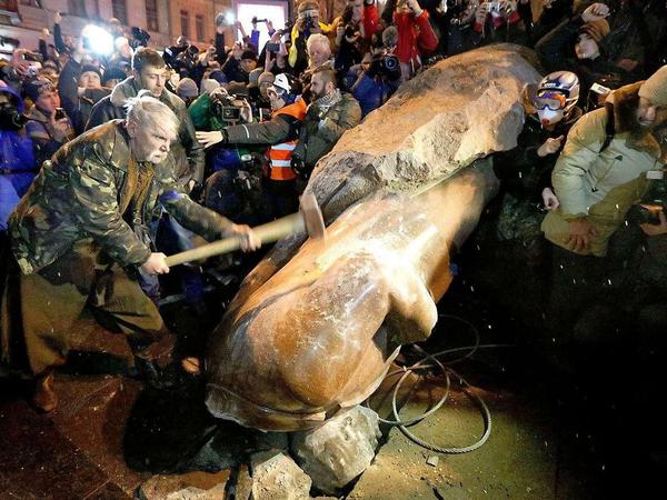 Demonstranten zerstören die Statue Lenins.