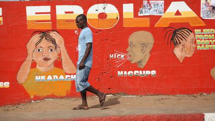 Ein Mann geht in Liberia an einem Gemälde vorbei, das Ebola-Symptome beschreibt. 