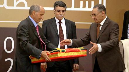 Mustafa Abdel Dschalil (links) übergibt die libysche Flagge an den Parlamentarier Mohammed Ali Salim.