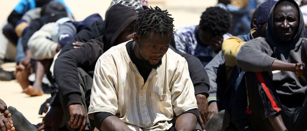  Migranten sitzen auf dem Boden an der Marinebasis in der libyschen Hauptstadt. 