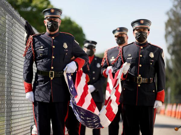 Charlie Eckert and Jorge Bittencourt von der Broward Fire Rescue Honor Guard tragen die amerikanische Flagge bei einer Gedenkveranstaltung.