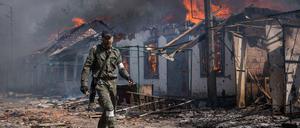 Ein prorussischer Kämpfer vor brennenden Häusern in der Region Luhansk