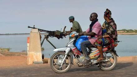 Die neue Normalität entlang des Nigers. Ein Motorrad fährt an einem Soldaten vorbei, der die Niger-Brücke von Markala bewacht. Die Brücke ist eine von drei festen Übergängen über den Fluss in Mali. Doch die Brücke bei Gao ist noch in den Händen der Islamisten. 