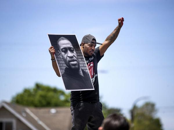 Ein Mann hält während einer Demonstration im Mai 2020 ein Foto von George Floyd hoch.