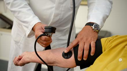 Ein Hausarzt misst den Blutdruck bei einer Patientin. Nach Ansicht von Sachverständigen sollten in Deutschland künftig auch "Teilkrankschreibungen" möglich sein. 
