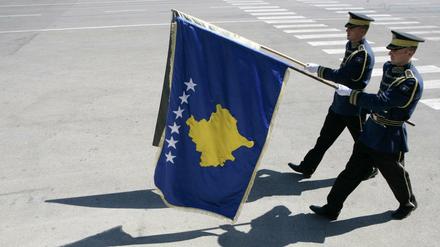 Die Fahne Kosovos von Paradesoldaten am Flughafen in Pristina.
