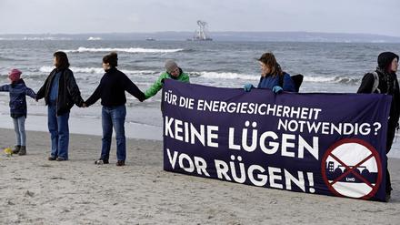 Mit einem Transparent und der Aufschrift „Für die Energiesicherheit notwendig? Keine Lügen vor Rügen“ stehen Menschen am Strand von Binz auf der Insel Rügen in einer Menschenkette als Protest gegen ein für die Insel vorgesehenes Flüssigerdgas-Terminal.  
