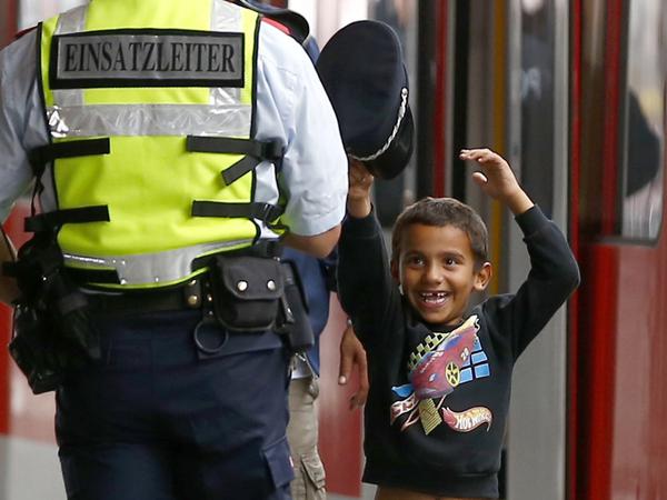 Ein Flüchtlingsjunge probiert auf dem Bahnhof in München die Mütze eines Sicherheitsbeamten der Deutschen Bahn an.