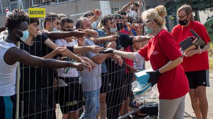 Litauer versorgen Migranten, die hinter dem Zaun eines Flüchtlingslagers stehen. 