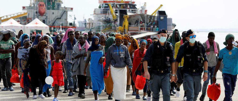 Italienische Polizisten begleiten Flüchtlinge im Hafen der sizilianischen Stadt Augusta.