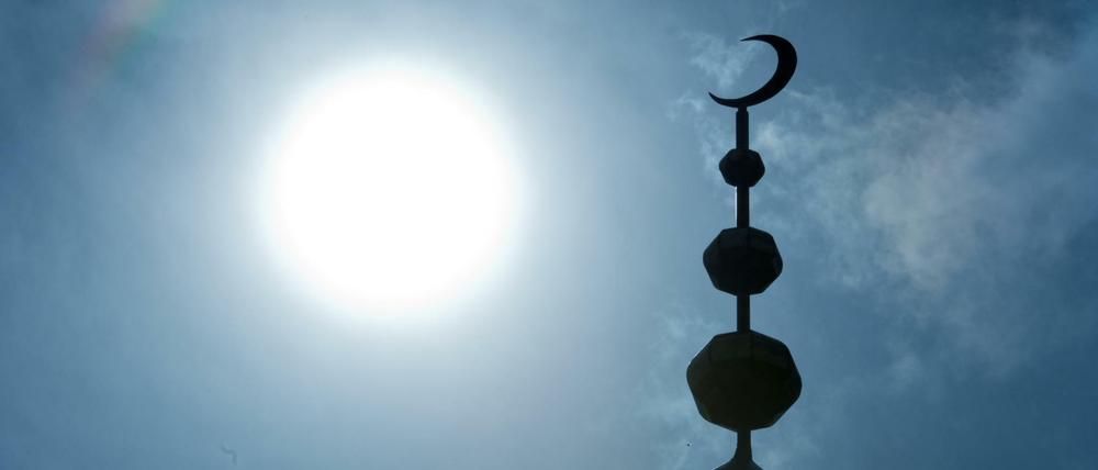 Der Halbmond auf dem Minarett der Abubakr Moschee in Frankfurt (Hessen) hebt sich als Schattenriss vor der Sonne ab.