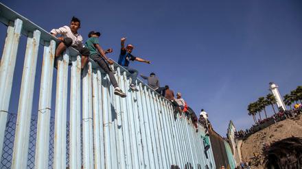 Migranten aus Mittelamerika sitzen nach einer Tausende Kilometer langen Reise auf dem Grenzzaun zwischen Mexiko und den USA.