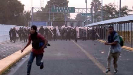  Migranten aus Mittelamerika laufen während Zusammenstößen mit der Polizei nahe der Grenze zwischen Guatemala und Mexiko vor mexikanischen Beamten weg.