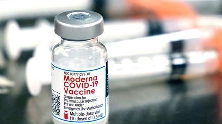 Ein Fläschchen des Moderna-Impfstoffes steht neben Spritzen (Symbolbild).