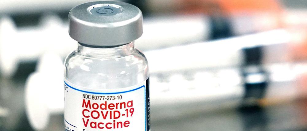 Ein Fläschchen des Moderna-Impfstoffes steht neben Spritzen (Symbolbild).