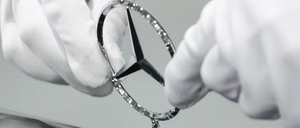 Sauber bleiben: Ein Fabrikarbeiter justiert den Stern an einem neuen Mercedes.