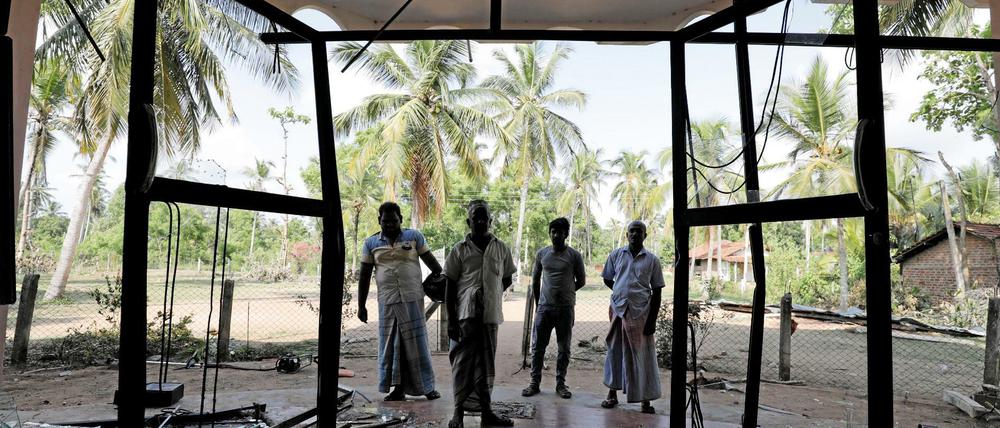 Unruhen aus Sri Lanka: Muslime stehen vor einer von Randalierern demolierten Moschee. 