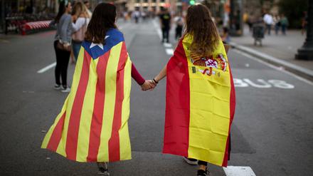 Hoffen auf Eintracht: Zwei junge Frauen, in die spanische Nationalflagge (rechts) sowie die katalanische Flagge "Estelada" gehüllt 