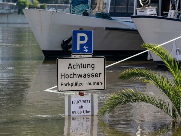 "Achtung Hochwasser - Parkplätze räumen" steht auf einem Schild im Hochwasser der Donau.