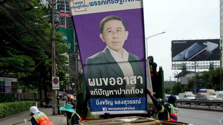 Arbeiter stapeln Wahlplakate am Straßenrand in Bangkok.
